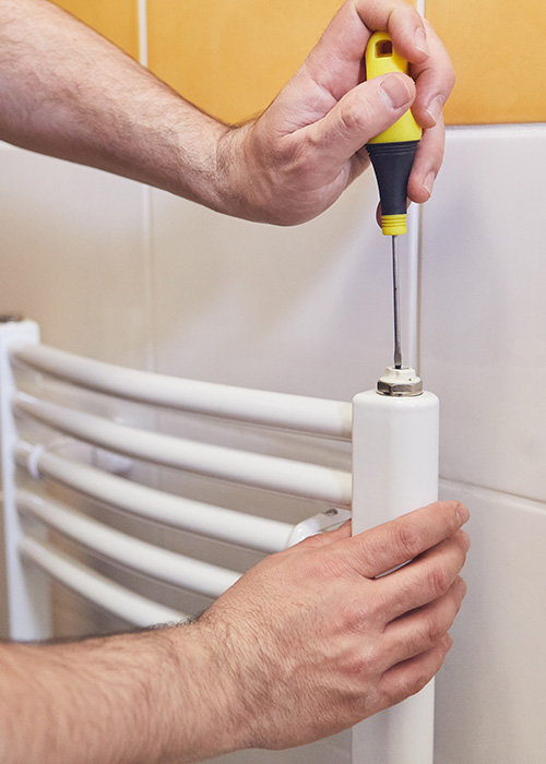 Installateur schraubt an moderner Badheizung